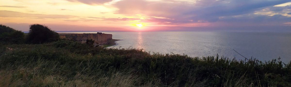 Wandern in der Bretagne: Blick von Klippe auf's Meer und untergehende Sonne