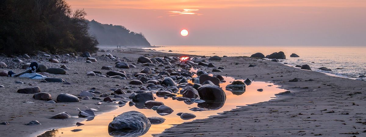 Strand auf Rügen, am Horizont wandern zwei Menschen